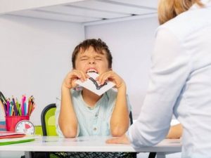 An adult looking at a child, who's trying to eat a card with the number seven on it.