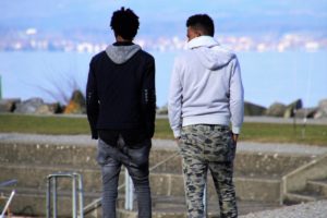 The backs of two people walking by some stairs in an urban park.