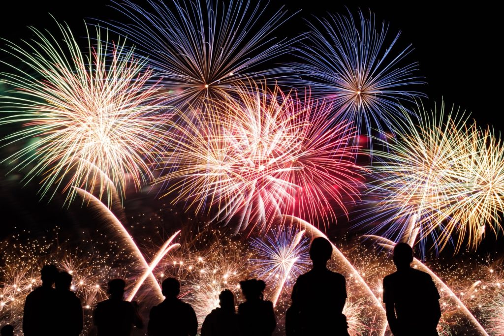 Red and yellow fireworks set against a black sky over a crowd of people in silhouette.
