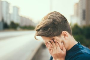 Closeup of person's head, hands over their eyes, looking exhausted.