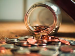 Close-up on assorted coins spilling out of a jar.