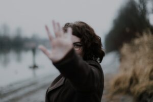 Person stretching their hand out towards the camera, covering their face from the lens.