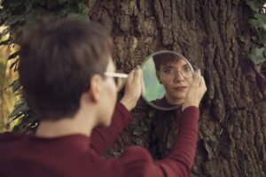 Someone looking at themself through a mirror on a tree.