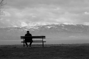 A landscape photo of someone sitting alone on a cloudy day.