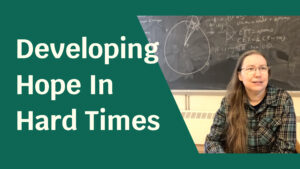 A woman in front of a chalk board, surrounded by a green foreground. Text next to her reads: "Developing Hope In Hard Times".