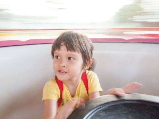 Close-up on a child spinning in a teacup amusement park ride.