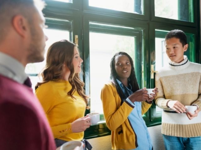 Group of four people holding cups, facing each other.