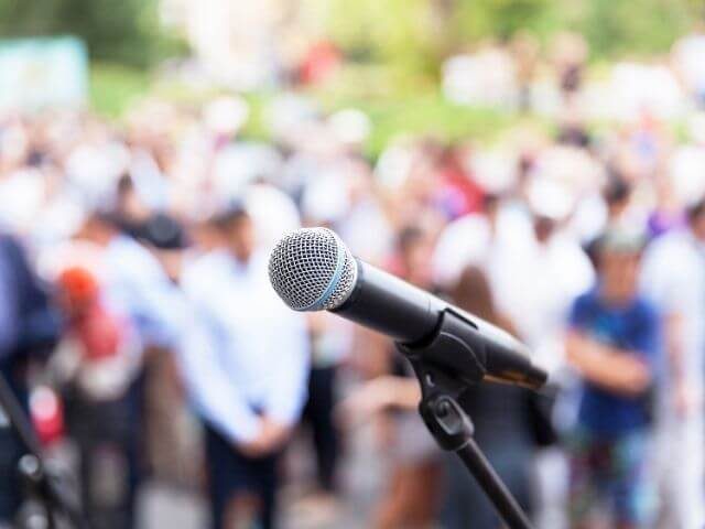 Close-up on a microphone in front of a blurred out crowd.
