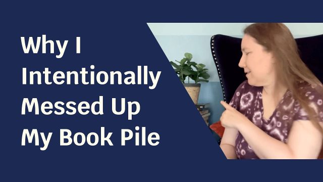 Blue solid foreground with text "Why I Intentionally Messed Up My Book Pile" and to the side a picture of a woman pointing at a stack of books behind her.