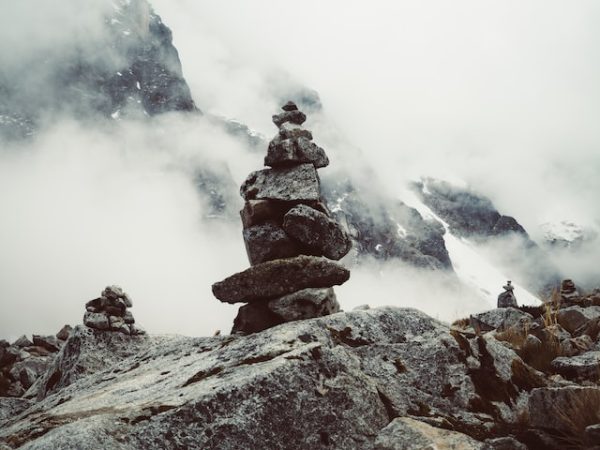 A pile of rocks balancing on one another, set against a watery storm in the background.