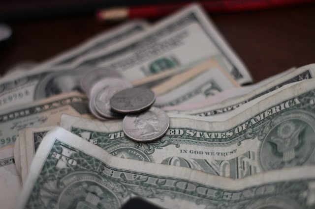 A spread of dollar bills, with a couple coins scattered on top.