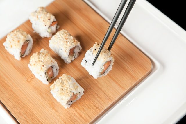 Close-up on black chopsticks picking up a sushi role.