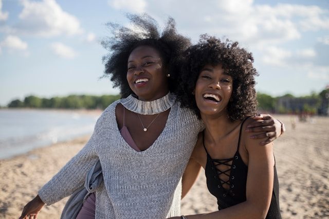 Two people smiling and side-hugging on a beach.