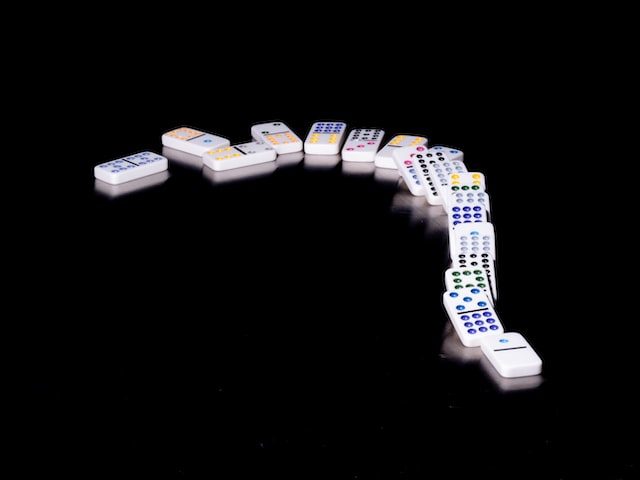 Line of white dominoes on a curve, knocked over.