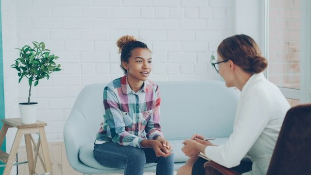 Person sitting on a couch talking to someone sitting across from them.