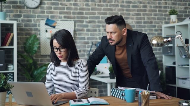 Someone typing on a computer while another person watches the screen.